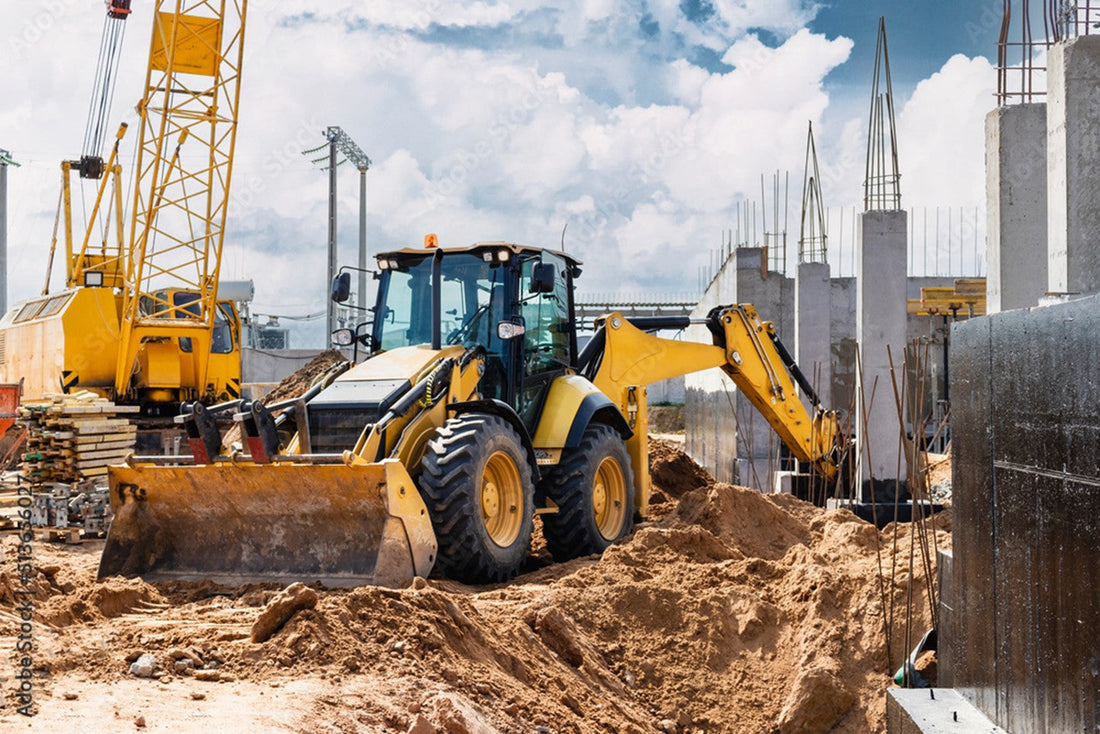 Wheel loader and crawler crane working in an urban construction site.